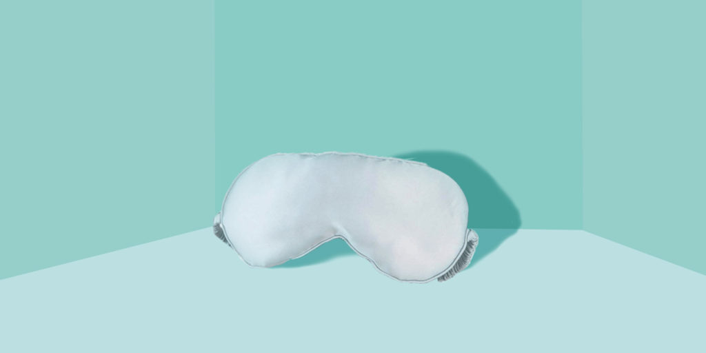 A white fluffy eye mask on a blue table